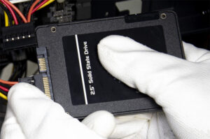 Image of gloved hands holding a solid state hard drive.