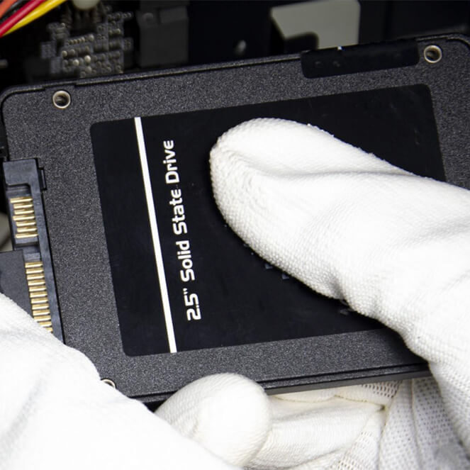 Image of gloved hands holding a solid state hard drive.